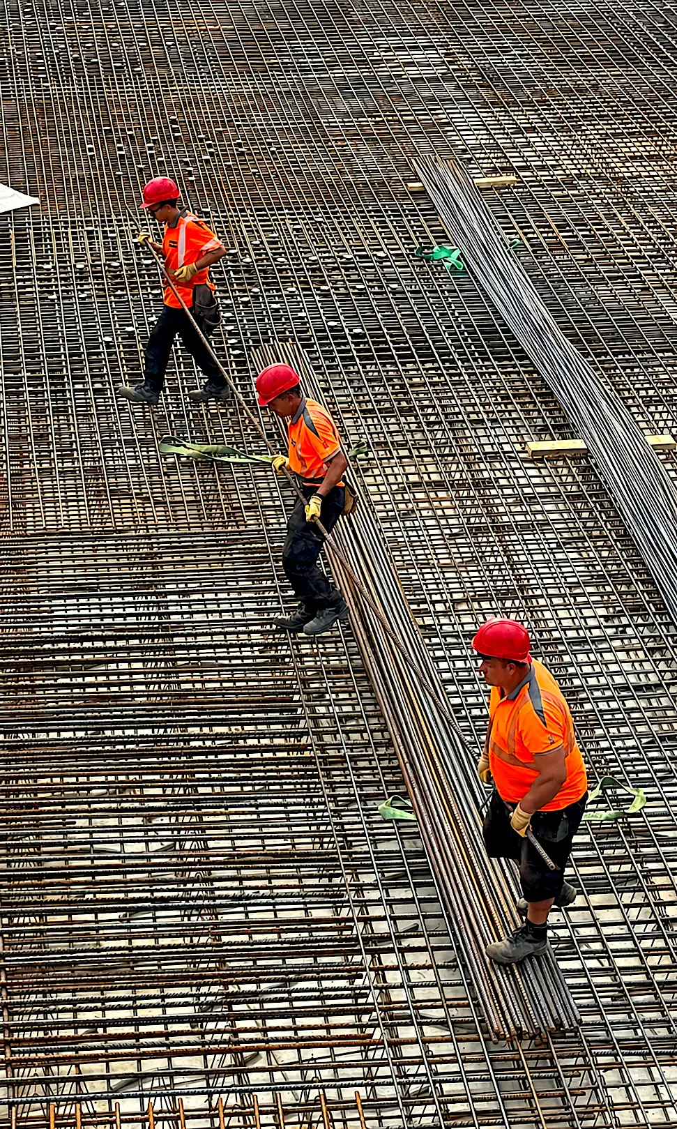 Drei Mitarbeiter von MAT BAU verlegen Bewehrungsstahl für eine Betondecke.